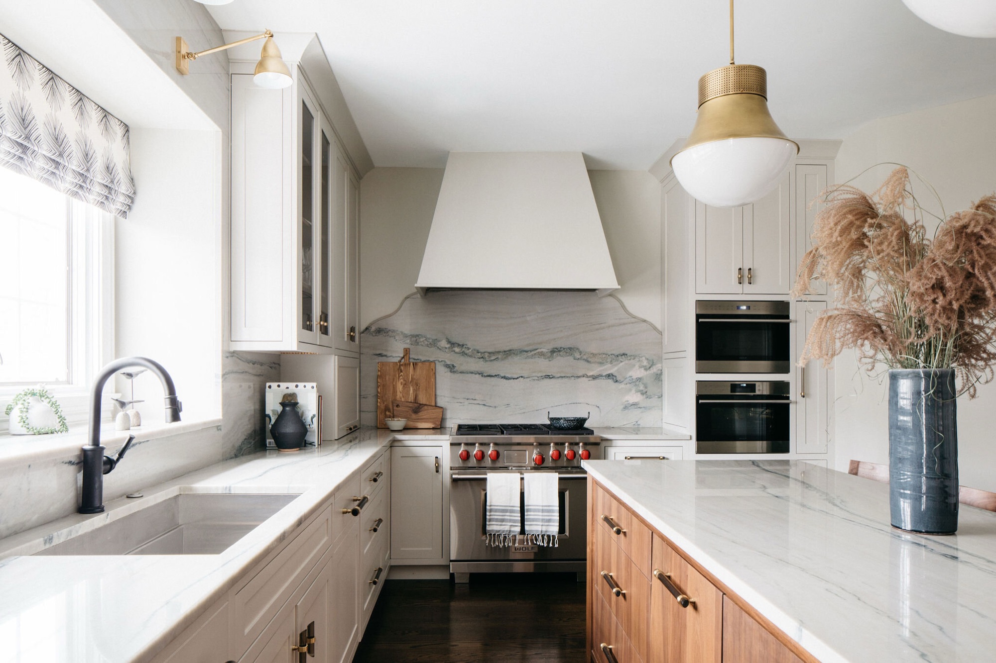 Cream and white kitchen with brass pendant lighting and marble counters designed by Leah Phillips Interiors