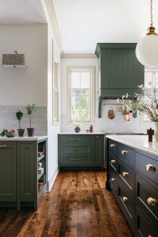 Kitchen with green cabinetry, black island and brass hardware designed by Leah Phillips Interiors