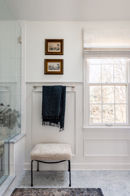 Bath detail with framed art, bench and marble shower beyond designed by Leah Phillips Interiors