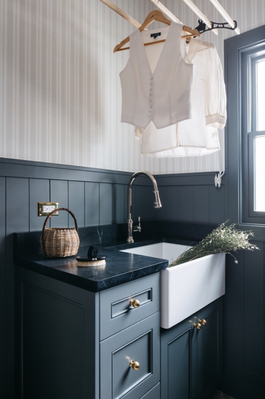 Navy laundry room with farmhouse sink and drying rail designed by Leah Phillips Interiors