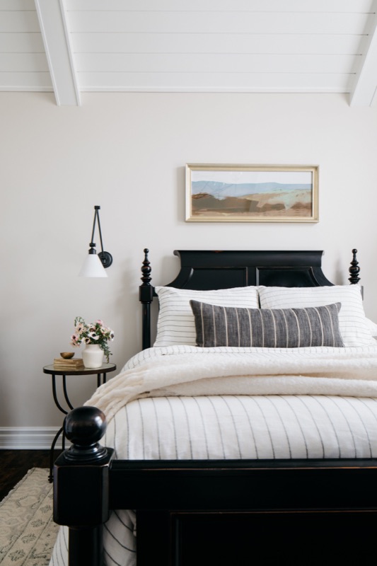 Bedroom with black four-poster bed and layered white bedding designed by Leah Phillips Interiors