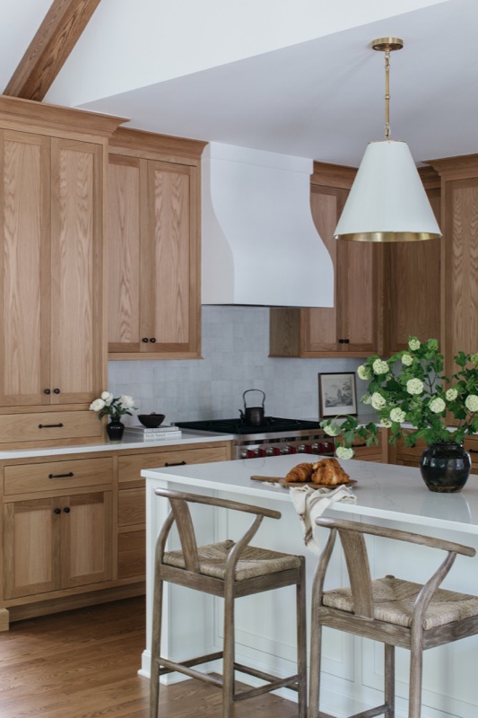 White oak kitchen with vaulted ceiling and white stools designed by Leah Phillips Interiors