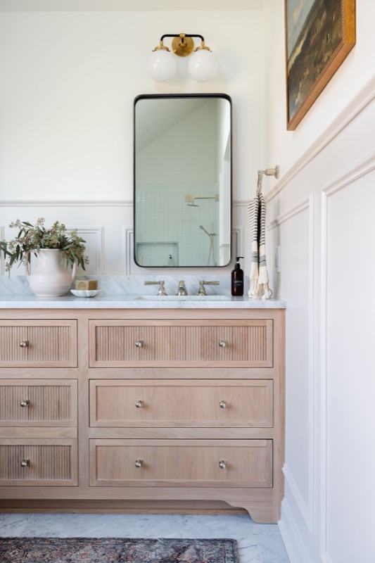 White oak vanity with black-framed mirror and greenery · Bathroom Renovations by Leah Phillips Interiors
