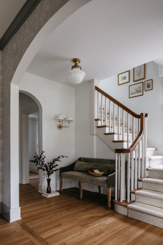 Stair hall with arched opening and green entry bench · Downers Grove Main Level Renovation by Leah Phillips Interiors