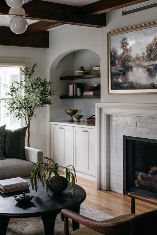 Fireplace wall with cream built-ins and landscape painting · Downers Grove Main Level Renovation by Leah Phillips Interiors