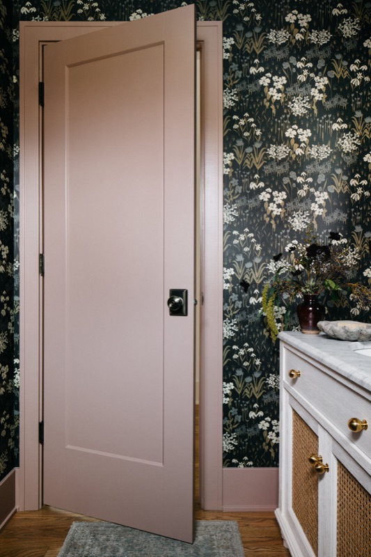 Blush pink door against dark floral powder room walls · Downers Grove Main Level Renovation by Leah Phillips Interiors