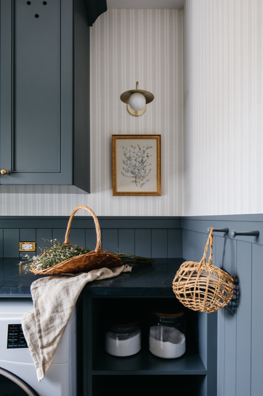 Laundry storage wall in navy beadboard with baskets · Downers Grove Main Level Renovation by Leah Phillips Interiors