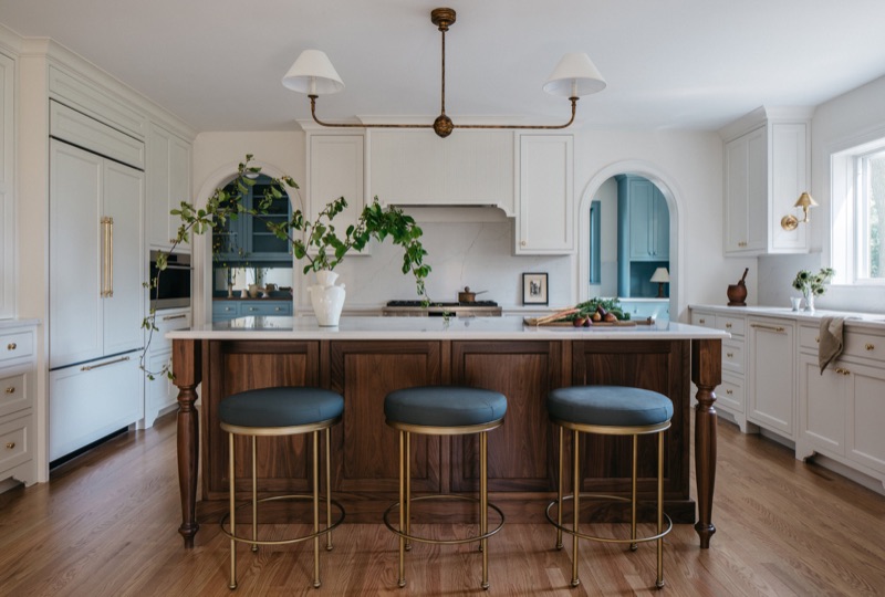 Walnut island with brass-ringed counter stools and linear pendant · Glen Ellyn Kitchen & Bathroom Renovation by Leah Phillips Interiors