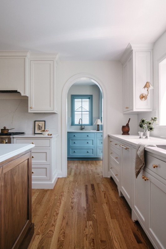 Long view of the cream kitchen with blue accents · Glen Ellyn Kitchen & Bathroom Renovation by Leah Phillips Interiors