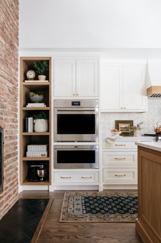 Wall ovens set into brick with open oak shelving · Glen Ellyn Main Level Renovation by Leah Phillips Interiors