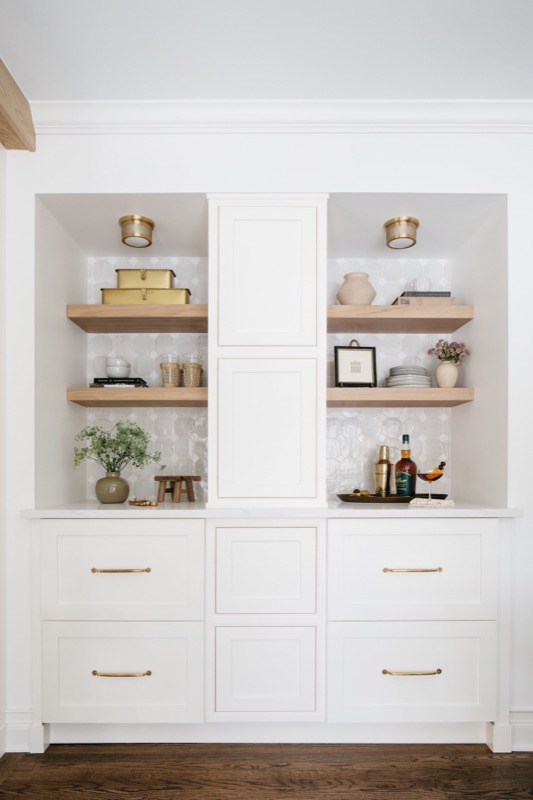 White built-in shelving styled with wood and brass · Glen Ellyn Main Level Renovation by Leah Phillips Interiors