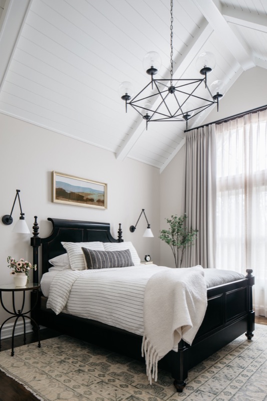Primary bedroom with black four-poster bed and geometric chandelier · Glen Ellyn Main Level Renovation