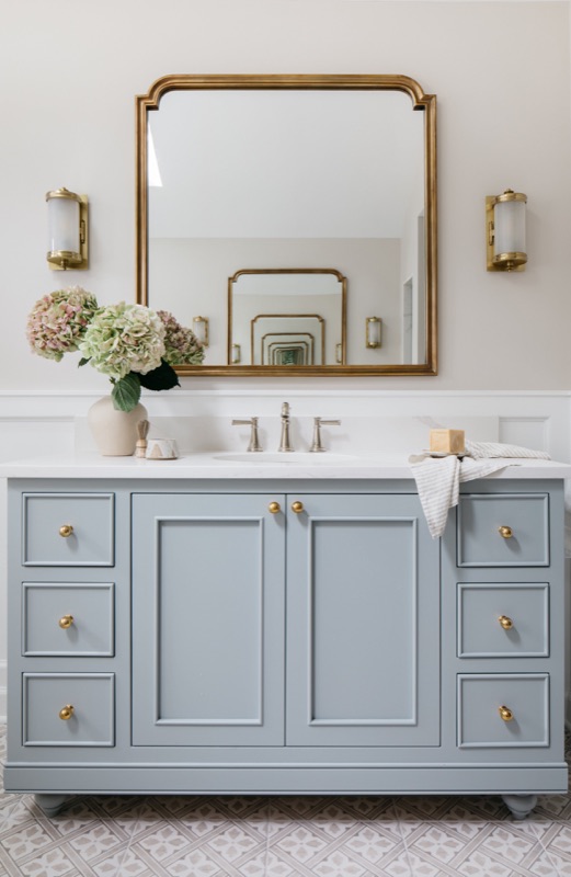 Blue-gray vanity with arched brass mirror and marble top · Glen Ellyn Primary Bathroom Renovation