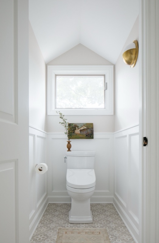 Water closet with wainscot and brass sconce · Glen Ellyn Primary Bathroom Renovation by Leah Phillips Interiors