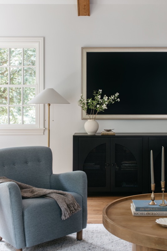 Family room media wall with blue armchair and black console · Glenview Home Renovation by Leah Phillips Interiors