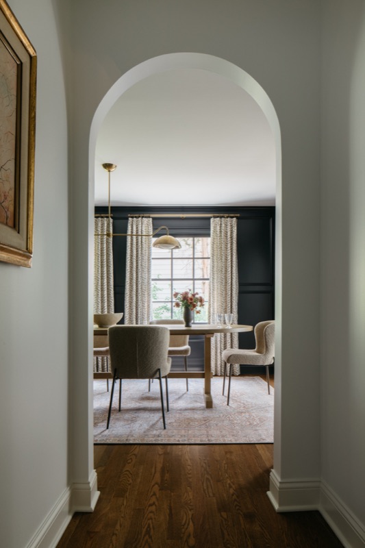 Arched doorway into the black-paneled dining room · Glenview Home Renovation by Leah Phillips Interiors