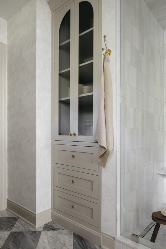 Built-in bath storage with arched glass cabinet · Glenview Home Renovation by Leah Phillips Interiors
