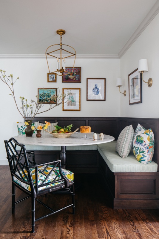 Banquette corner with black bamboo chairs and gallery art · Glenview Kitchen Addition & Renovation by Leah Phillips Interiors