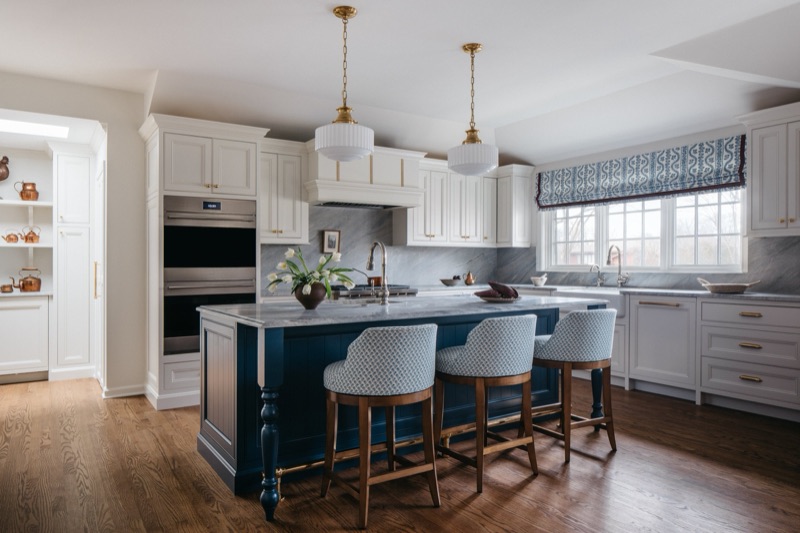 Kitchen with navy island, brass pendants and window seat banquette · Glenview Main Level Renovation by Leah Phillips Interiors