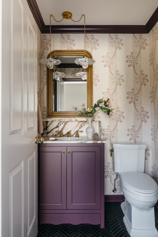 Powder room with plum vanity and trailing floral wallpaper · Glenview Main Level Renovation by Leah Phillips Interiors