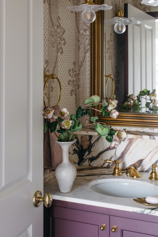 Powder room detail with antique brass mirror and marble top · Glenview Main Level Renovation by Leah Phillips Interiors