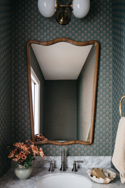 Powder room with deep green wallpaper and antique mirror · Lincoln Park Main Level Renovation by Leah Phillips Interiors