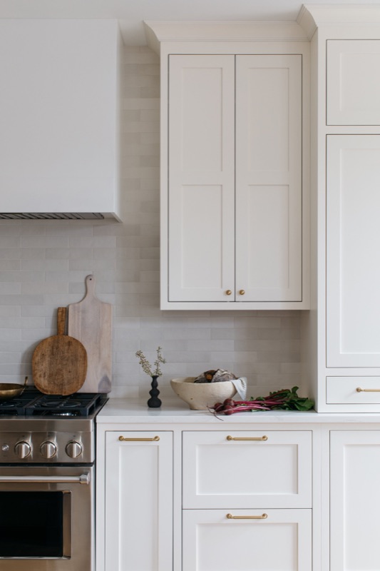 Range wall with crisp white cabinetry and marble backsplash · Lincoln Park Renovation by Leah Phillips Interiors