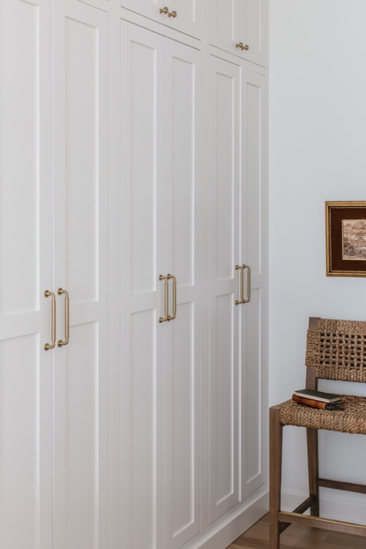 Full wall of white pantry storage with cane-back chair · Lincoln Park Renovation by Leah Phillips Interiors