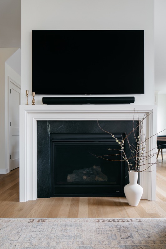 Fireplace wall with black marble surround and media cabinet · Lincoln Park Renovation by Leah Phillips Interiors