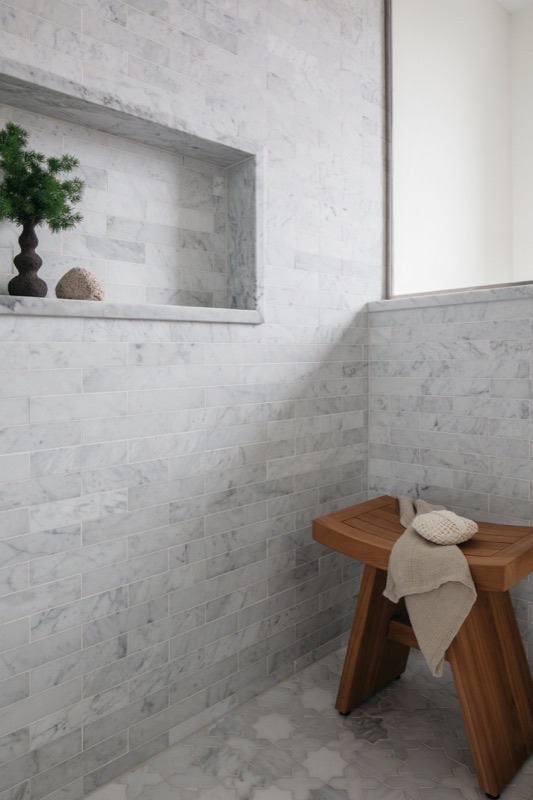 Marble walk-in shower with bench and storage niche · Lincoln Park Renovation by Leah Phillips Interiors