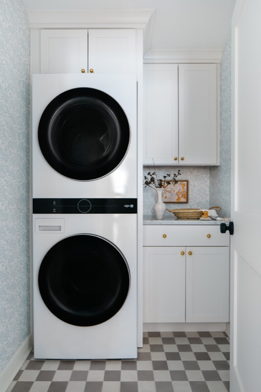 Stacked laundry with checkerboard tile floor · Lincoln Park Renovation by Leah Phillips Interiors
