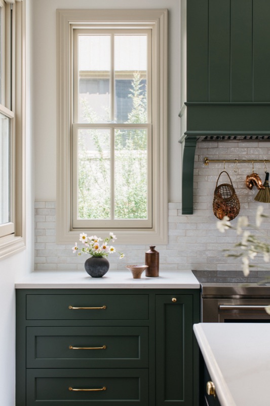Green cabinetry detail at the window with marble backsplash · Oak Park Main Level Renovation by Leah Phillips Interiors