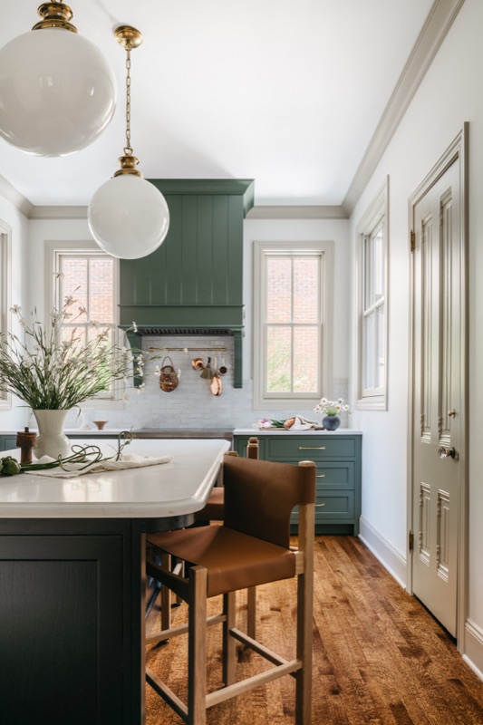 Kitchen island with leather counter stool and globe pendants · Oak Park Main Level Renovation by Leah Phillips Interiors