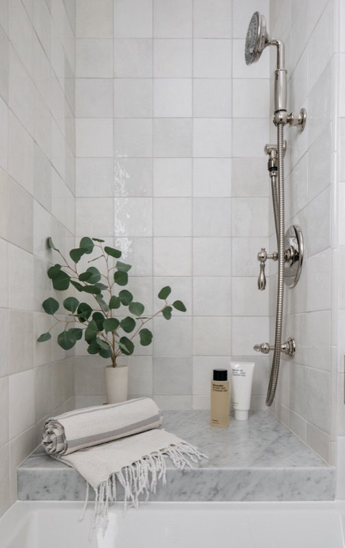 Marble shower with rain column and eucalyptus styling · Wilmette Bathroom & Laundry Renovation by Leah Phillips Interiors