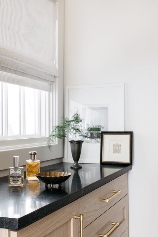 Black quartz counter detail with brass accents · Wilmette Bathroom & Laundry Renovation by Leah Phillips Interiors