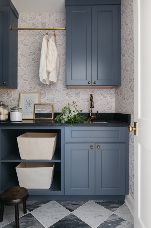 Laundry storage with open shelves and canvas bins · Wilmette Bathroom & Laundry Renovation by Leah Phillips Interiors
